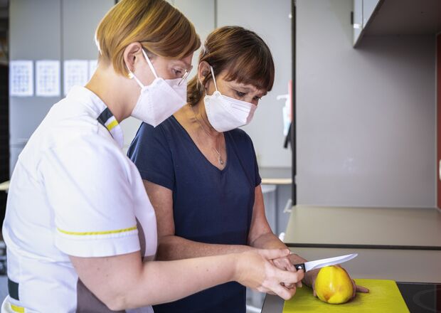 Patiënt leert snijden op SP-revalidatie samen met verpleegkundige