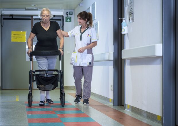 Patiënt wandelt op de gang onder begeleiding 