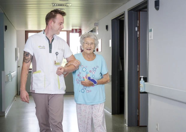 Verpleegkundige wandelt op de gang met patiënte geriatrie 